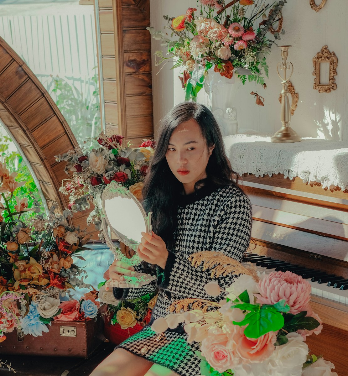 a woman sitting in front of a mirror next to a piano