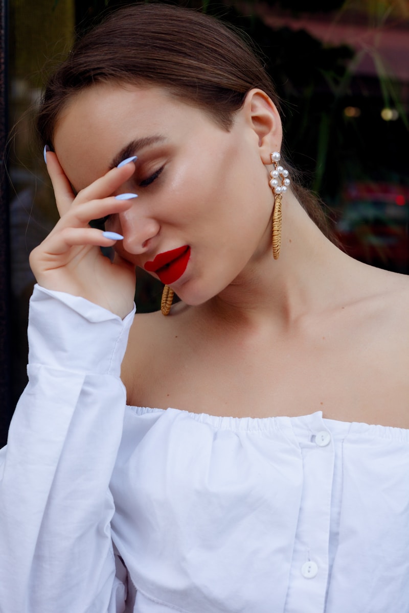 A woman in a white shirt holding her hand to her face
