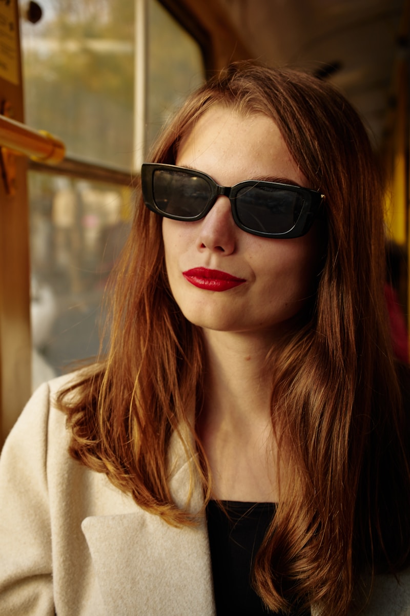 A woman wearing sunglasses and a coat on a train