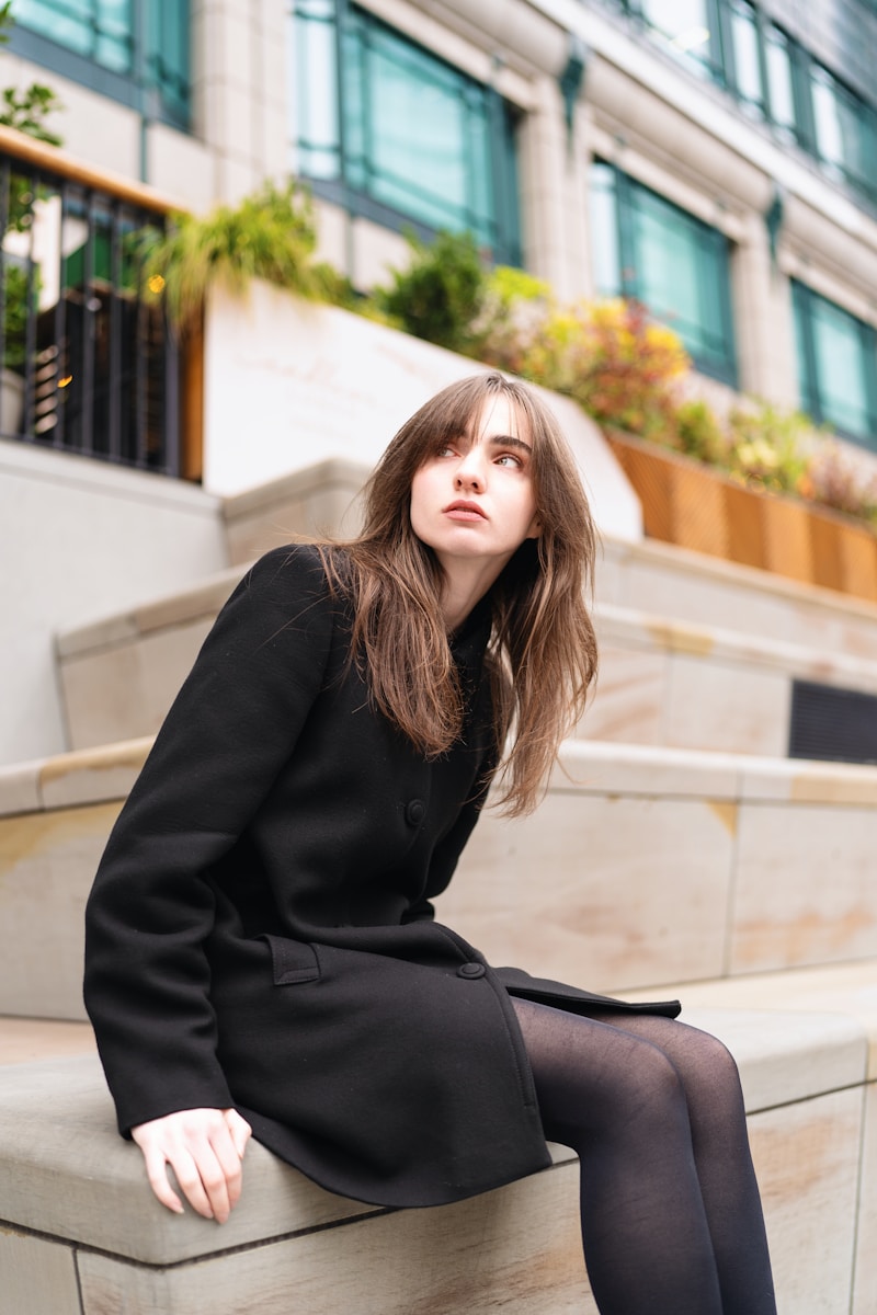 A woman in a black dress is sitting on a ledge