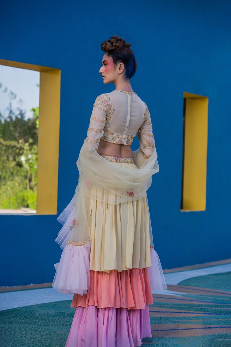 Woman in tiered pastel dress against blue wall.